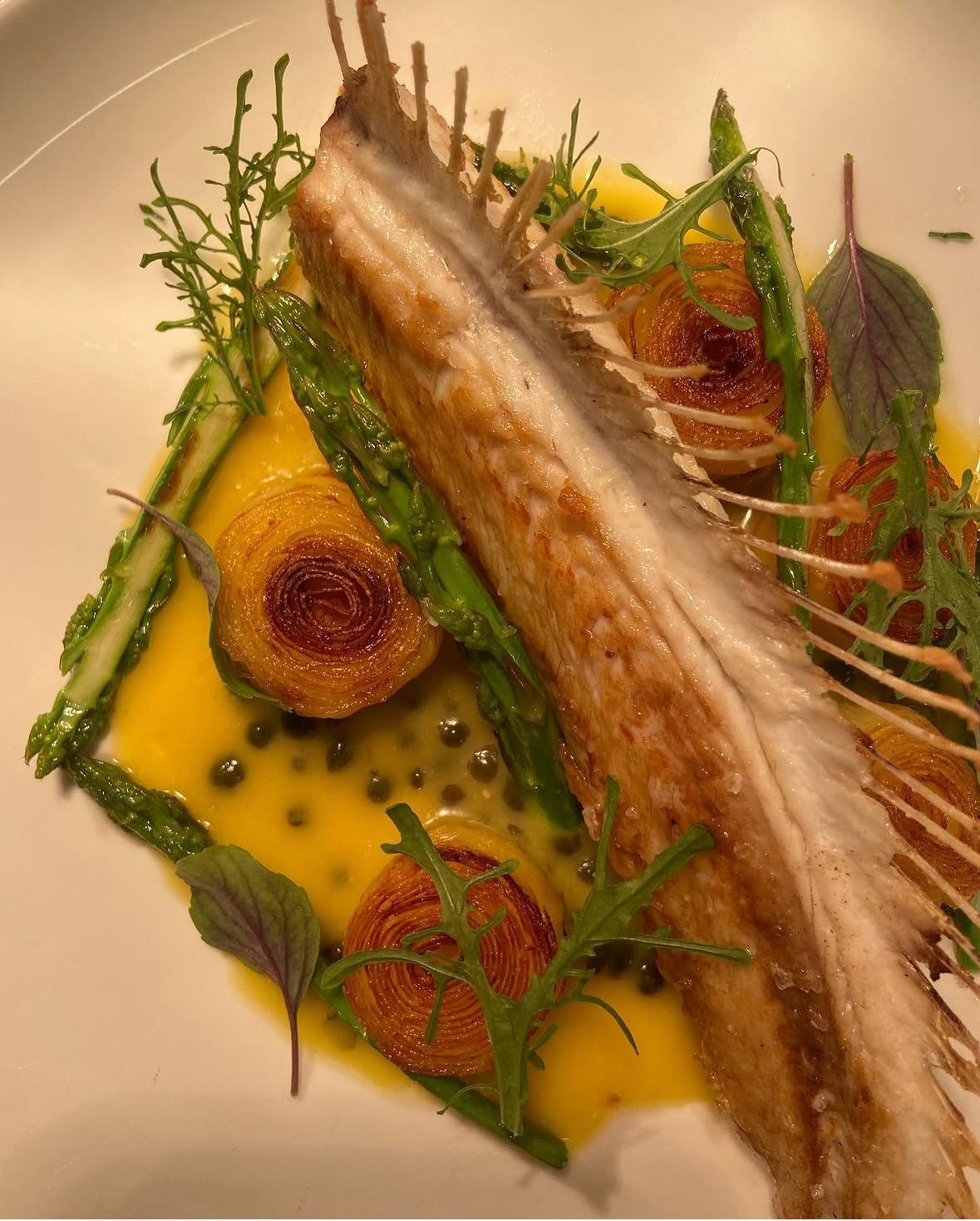 Pan-roasted fish over saffron sauce with caper and potato roses